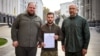 Parliament Speaker Ruslan Stefanchuk, Ukrainian President Volodymyr Zelenskiy, and Prime Minister Denys Shmyhal pose with a request for fast-track membership to the NATO military alliance in Kyiv on September 30, 2022.