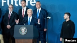 U.S. President Joe Biden speaks at the conclusion of the NATO summit in Washington on July 11, as Ukrainian President Volodymyr Zelenskiy (right) and other other foreign leaders look on.