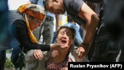 A Kazakh police officer (right) detains an opposition supporter in Almaty on June 10.