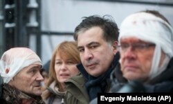 Former Georgian President Mikheil Saakashvili (center) speaks to people wounded during clashes with police in Kyiv on December 6.