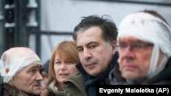 Former Georgian President Mikheil Saakashvili (center) speaks to people wounded during clashes with police in Kyiv on December 6.