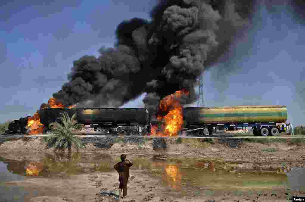 A boy watches a plume of smoke rising from fuel trucks after they were attacked by unidentified gunmen on a highway near Shikarpur, Pakistan in 2011.