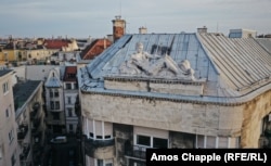 A reclining rooftop character stands opposite St. Stephen's Basilica.