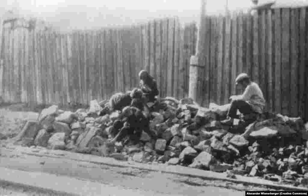 Besprisornyje sitting on a stone-heap, delousing themselves