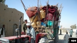 Afghan police check residents fleeing Marjah as they arrive in Lashkar Gah, in Helmand Province, on February 8.