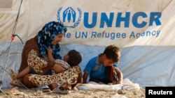 A Syrian mother and her two children rest at a new refugee camp on the outskirts of the city of Irbil in Iraq's Kurdish region.