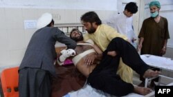 Relatives move a victim onto a bed as he receives treatment at a hospital following multiple explosions that targeted a cricket stadium in Jalalabad on May 19. Eight people were killed.