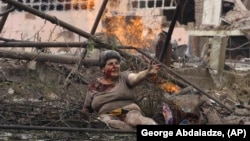 A wounded Georgian woman lies with other people in front of an apartment building hit by a Russian air strike in the northern Georgian town of Gori on August 9, 2008.