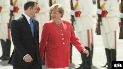 Moldovan Prime Minister Vlad Filat (left) walks with German Chancellor Angela Merkel during a welcoming ceremony at Chisinau airport.