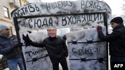 A young activist wearing a mask of Ukrainian President Viktor Yanukovych invites passersby to go through a symbolic gate with the words "Customs Union" and "Abandon Hope, All Ye Who Enter Here," during a protest in front of the presidential office in Kyiv in December.