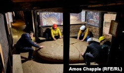 Bosnian tourists are instructed by a guide (left) to feel the “energy” of what Osmanagic claims is a man-made ceramic plate in the Visoko tunnels.