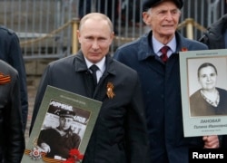 Russian President Vladimir Putin holds a portrait of his father, Vladimir Spiridonovich, as he takes part in the Immortal Regiment march in Moscow on May 9.