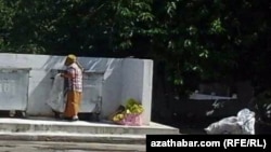 A woman picks through garbage cans in Ashgabat.