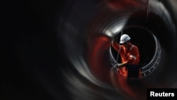 A worker is seen through a pipe at the construction site of the Nord Stream 2 gas pipeline, near the town of Kingisepp, Russia.