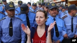 A Belarusian woman applauds in front of a police line as part of a creative antiregime protest, one of many to have taken place in the country in recent weeks.