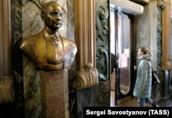 A woman enters Yeliseyevsky past a bust of its founder on April 11, the shop's last day of business.