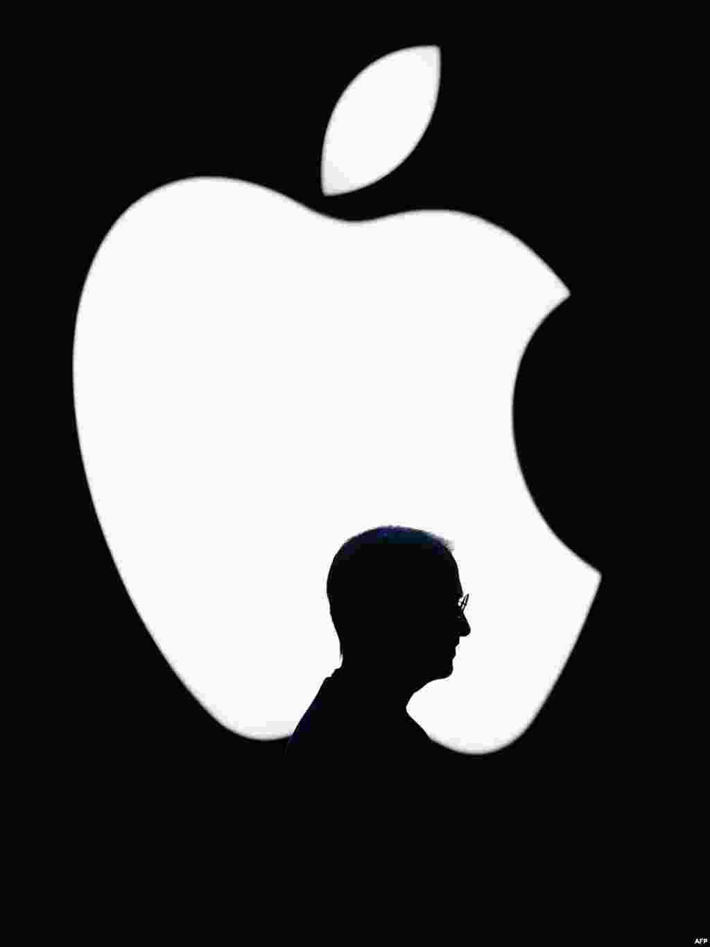 Jobs is silhouetted by an Apple logo at the 2004 Worldwide Developers Conference in San Francisco in June 2004.