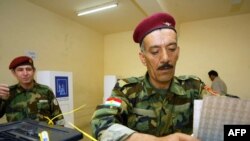 An Iraqi Kurd peshmerga drops his ballot at a polling station in Irbil