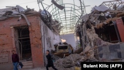 Local residents walk past what was reportedly damage from a missile strike in the Azerbaijani city of Ganca on October 8.