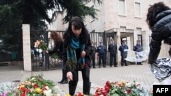 People put flowers in front of the building where three people were killed in an anti-government protest.