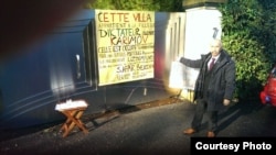 Uzbek dissident Safar Bekjon stands next to the sign identifying Gulnora Karimova's house in Geneva on December 23.