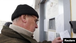 A man fills in a form detailing the contents of his parcel before he's allowed to pass it to a detained opposition activist inside a prison in Minsk on December 22.