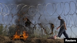 A Hungarian policeman walks past burning clothes belonging to Syrian migrants on a border fence between Serbia and Hungary near the village of Horgos on August 28.