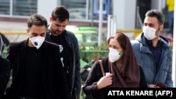 Some Iranians, like these waiting to cross a street in the capital Tehran, have started wearing masks to protect themselves against the spread of the virus. 