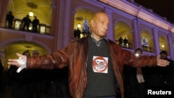 An opposition activist wearing a Vladimir Putin mask and a T-shirt reading "Against the Party of Swindlers and Thieves."