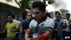 Iranians react as a protestor is wounded at the opposition rally in Tehran on June 15