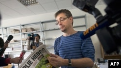 The publisher of the French satirical weekly "Charlie Hebdo," known only as Charb, answers questions posed by journalists as he holds the latest edition of the magazine in Paris on September 19.