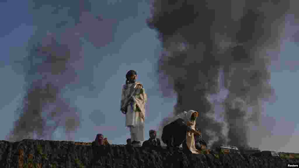 Smoke rises past residents standing on the wall of a truck terminal where NATO fuel tankers were set ablaze in Quetta in December.