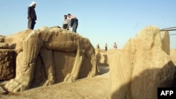 Iraqi workers clean a statue of a winged bull at an archaeological site in Nimrud in 2001.