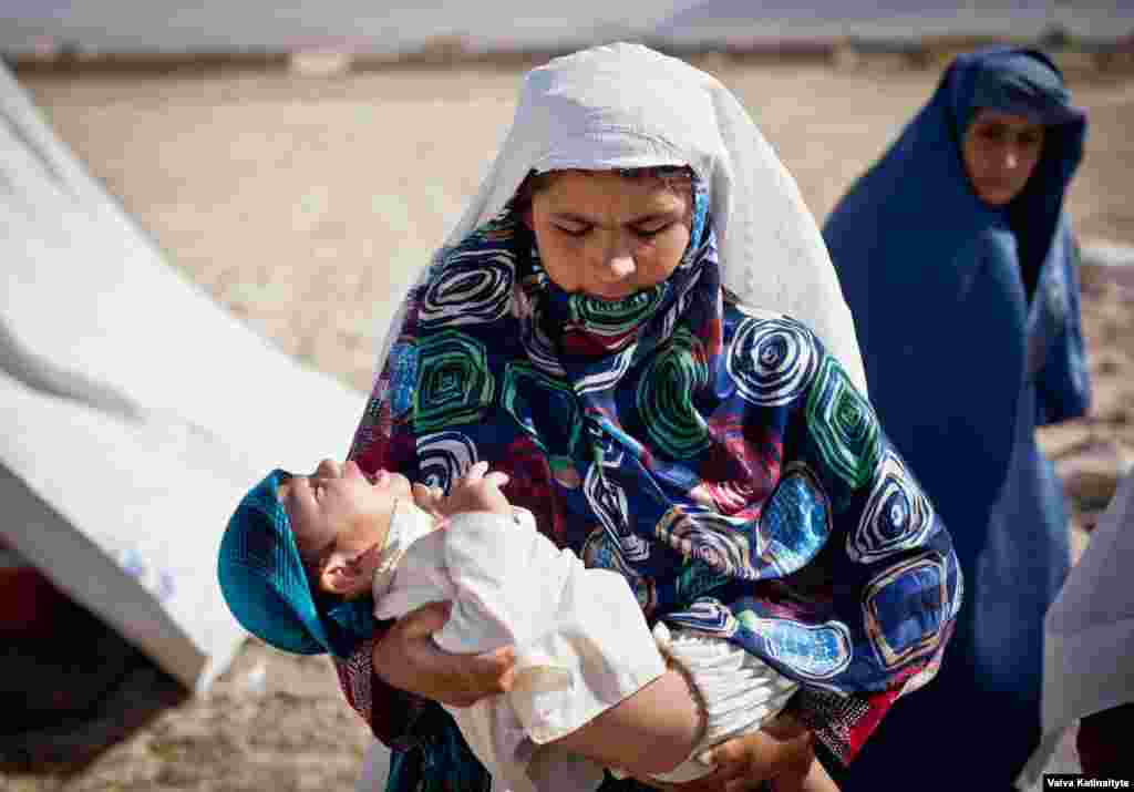 Homayra, a widow carrying her paralyzed child, lives in a makeshift refugee camp outside Mazar-e Sharif, Balkh Province. 