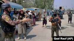 A Pakistani paramilitary soldier (left) and Afghan Taliban fighters stand guard on their respective sides of the border at a crossing in Torkham, in Pakistan's Khyber district. (file photo)