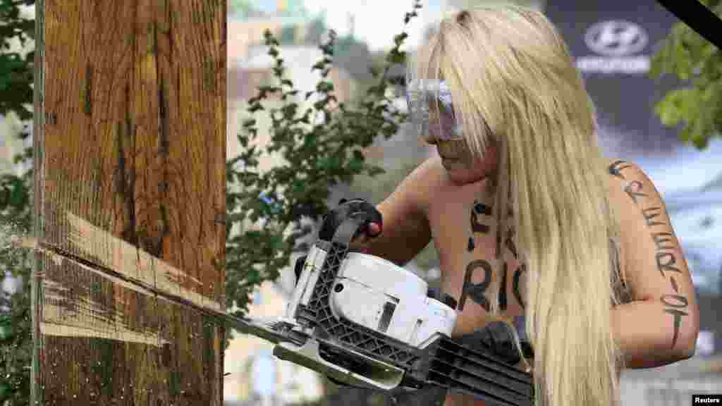 An activist from the women&#39;s rights group Femen uses a chainsaw to cut down a cross erected in memory of victims of political repression under Stalin in Kyiv to protest the Pussy Riot case.