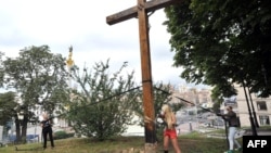 Femen activists use a chainsaw to cut down an Orthodox cross in Kyiv.