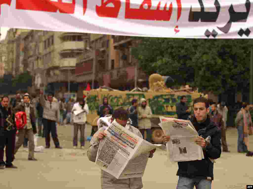 Protesters read newspapers under a banner reading "People Want The Regime To Fall" in Tahrir Square on February 5.