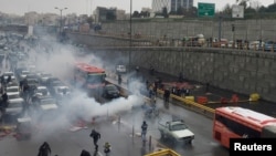 Riot police try to disperse people as they protest on a highway against increased gas prices in Tehran on November 16.