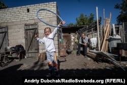 Toma, now 6, plays in the yard of her house, from where she can see Donetsk: Frontline positions are just a few hundred meters away.