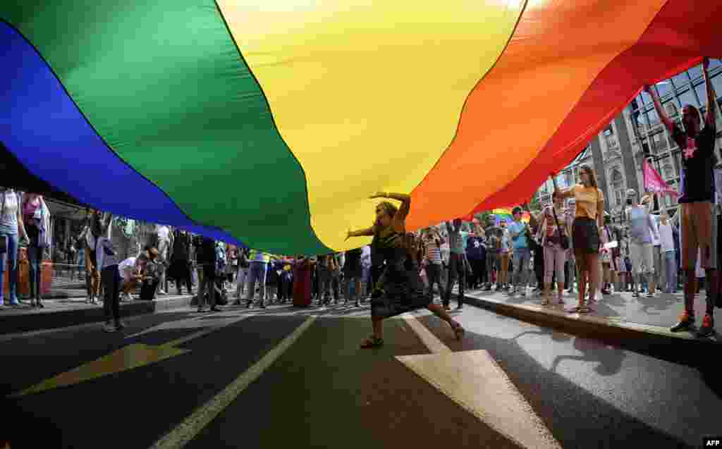 A woman dances under a huge rainbow flag during the good-humored festivities.&nbsp;