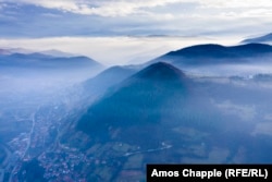 An aerial photo of Visoko and Visocica Hill shot in December. The town is shrouded in smoke from wood-burning fireplaces used for heating.