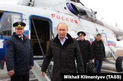 Putin emerges from a helicopter at the Krymsk air base in southern Russia in January 2013. An officer carrying a nuclear briefcase is saluting in the background.