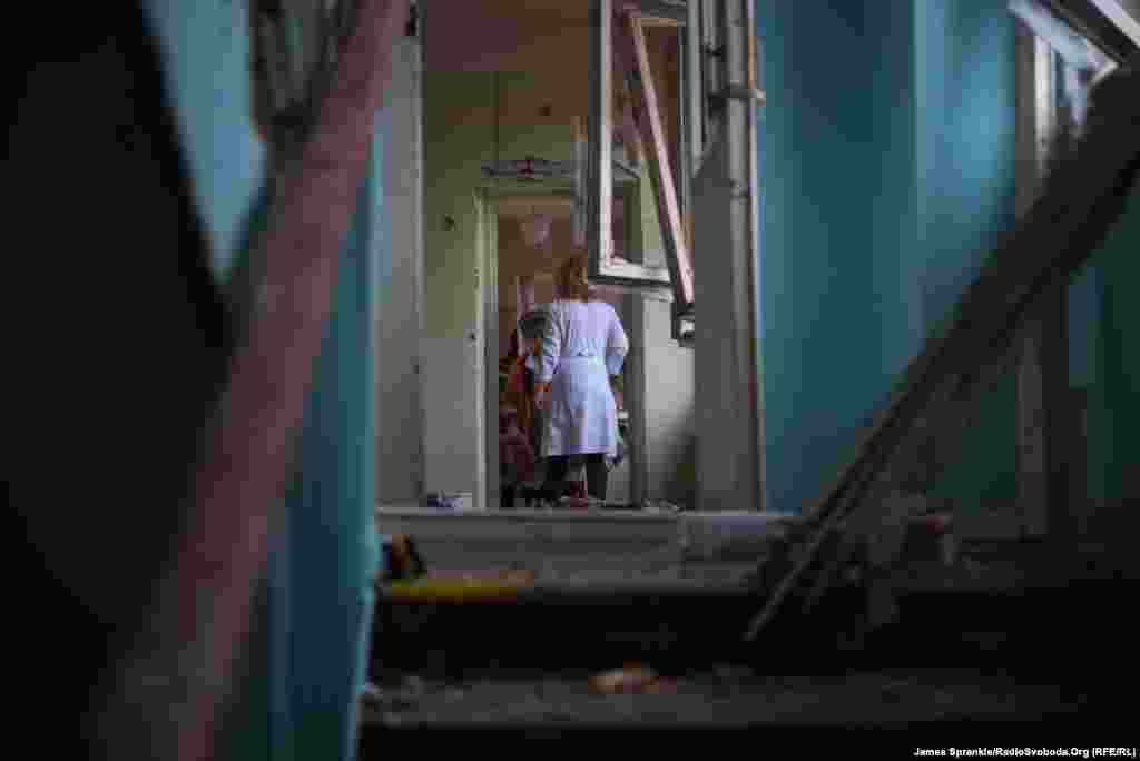 A medical professional and a patient, glimpsed from a ruined stairwell.