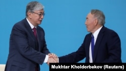 Kazakh interim President Qasym-Zhomart Toqaev (left) and former President Nursultan Nazarbaev shake hands at the congress of the ruling Nur Otan ruling party in Nur-Sultan on April 23. 