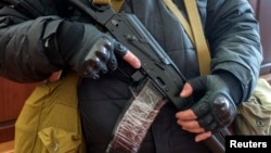 An armed man, believed to be a pro-Russian protester, stands guard inside the offices of the Ukrainian Security Service in Luhansk on April 7.