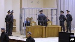 Surrounded by police, Dzmitry Kanavalau (left) and Uladzislau Kavalyou are seen in a cage during a court session in Minsk in mid-September.