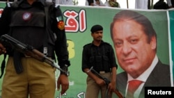 Police stand guard near a portrait of Nawaz Sharif during a campaign rally in Peshawar.