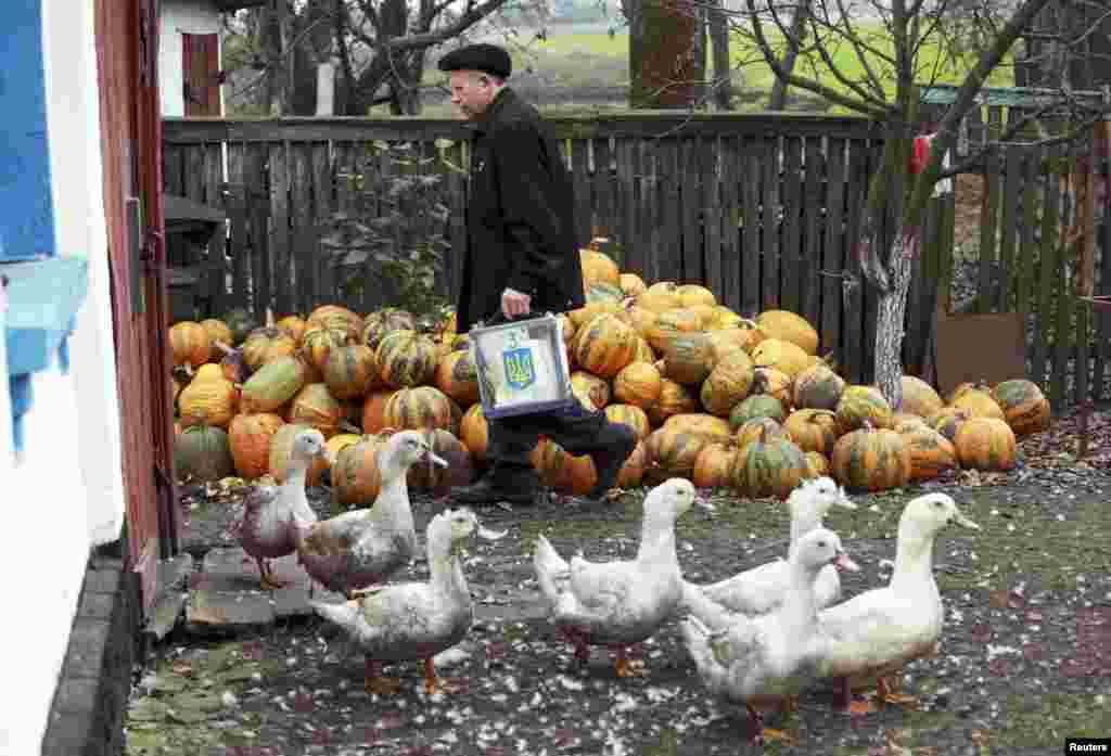 A member of a local election commission carries a ballot box in the village of Vilshanska-Novoselytsa, some 75 kilometers south of Kyiv. (REUTERS/Konstantin Chernichkin)