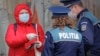 A woman shows identity papers to police officers enforcing a lockdown in Bucharest, which is about 360 kilometres from the northern city of Suceava.